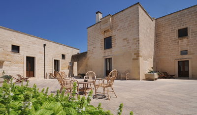 Sunlit stone courtyard of an accessible guesthouse with garden furniture