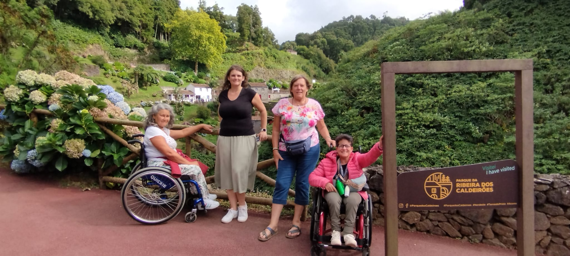 Group of travellers, two using wheelchairs, on an accessible path in a green park
